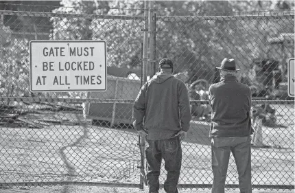  ?? JEFF FAUGHENDER/COURIER JOURNAL ?? Artists Ed Hamilton, right, and William Duffy stand at the locked gates of a city scrapyard on Lexington Road., looking for art they created for the city of Louisville in the mid-1990s as part of an award-winning, $3.2 million dollar Main Street makeover.