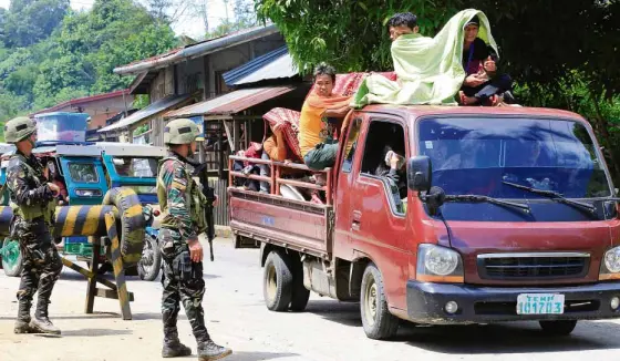  ?? —REUTERS ?? MILITARY CHECKPOINT Soldiers inspect vehicles carrying Marawi residents who are fleeing the city at a checkpoint in Pantar town in Lanao del Norte province.