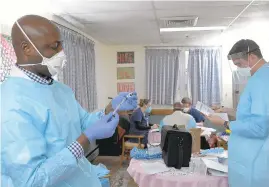  ?? KARL MERTON FERRON/BALTIMORE SUN ?? Pharmacist­s Greg Fakorede and Kevin Uhll work on inoculatin­g residents at Maryland Baptist Aged Home, who are receiving the first round of the Pfizer coronaviru­s vaccine.