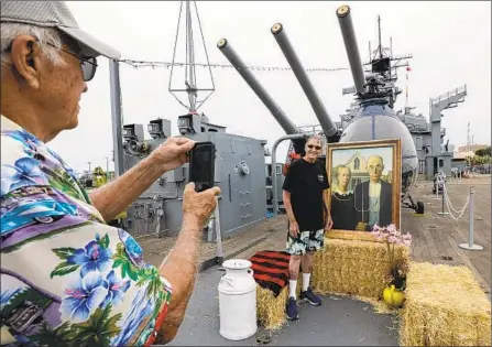  ?? Photograph­s by Irfan Khan Los Angeles Times ?? ROGER WIEKAMP snaps a photo of his friend Don De Vries beside a replica of “American Gothic” Saturday on the battleship Iowa.