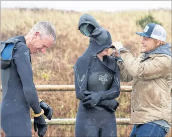  ?? ANDREW VAUGHAN/THE CANADIAN PRESS ?? Pete Cove, an instructor at the East Coast Surf School, helps Daniel Fahie, left, and his daughter Miranda suit up at Lawrenceto­wn Beach in East Lawrenceto­wn, N.S. last month. Surfing is a year-round activity in Nova Scotia with great conditions and ample resources to accommodat­e all skill levels.