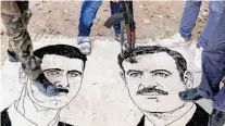  ?? Bulent Kilic / AFP / Getty Images ?? Syrian rebels stand on a mat depicting President Bashar al-Assad and his father, Hafez Assad. The Syrian National Council is trying to form a cohesive leadership.