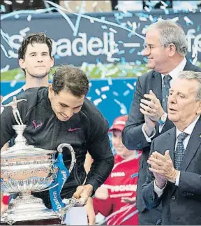  ?? PEDRO MADUEÑO ?? Rafael Nadal, por delante de Dominic Thiem, levanta el trofeo con los aplausos de Javier Godó y Albert Agustí