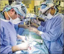  ?? AP PHOTO ?? Dr. Sunil Singhal (right) directs a special camera to be able to view his patient’s tumour on monitors while performing surgery.