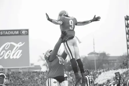  ?? Joshua L. Jones/Athens Banner-Herald via AP ?? ■ Georgia wide receiver Jeremiah Holloman (9) is lifted by offensive lineman Solomon Kindley (66) on Saturday after scoring a touchdown against Georgia Tech in the first half of an NCAA college football game in Athens, Ga.