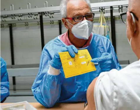  ?? Foto: Marcus Merk (Archivbild) ?? Dr. Thomas Brückmann klärt beim Impftag in Meitingen einen Mann auf und zeigt ihm den Vermerk in seinem Impfpass.