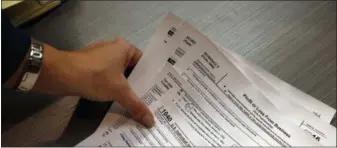  ?? BRENNAN LINSLEY — THE ASSOCIATED PRESS FILE ?? Tax preparatio­n firm owner Alicia Utley reaches for hard copies of tax forms in her offices at Infinite Tax Solutions, in Boulder, Colo.