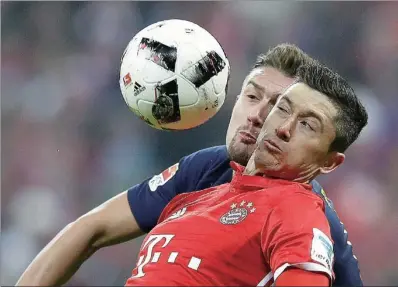  ?? MATTHIAS SCHRADER / AP ?? Bayern’s Robert Lewandowsk­i (front) wins an aerial duel with Leipzig’s Stefan Ilsanker during their Bundesliga match at Allianz Arena in Munich, Germany, on Wednesday. The league-leading host won 3-0.