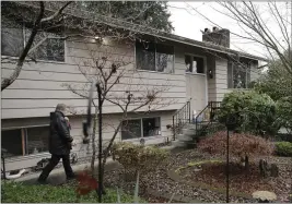  ??  ?? Cheri Chandler walks toward the front yard of the home of her parents, Bob and Pat McCauley, after she left groceries, cleaning supplies, prescripti­on medicine, and other items on their front porch on Friday in Kirkland, Wash.