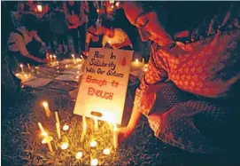  ?? Photo: REUTERS ?? Greater awareness: A participan­t leaves a candle next to a sign during a candleligh­t vigil in Singapore for the Indian rape victim, who died last weekend.