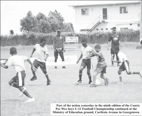  ?? ?? Part of the action yesterday in the ninth edition of the Courts Pee Wee boys U-11 Football Championsh­ip continued at the Ministry of Education ground, Carifesta Avenue in Georgetown.