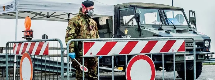  ??  ?? Divieto di entrata e uscita
Un militare dell’esercito davanti a uno dei posti di blocco nella città di Codogno, uno dei 10 Comuni del Lodigiano in isolamento dal 23 febbraio. Fino al 3 aprile l’intera Lombardia sarà zona rossa