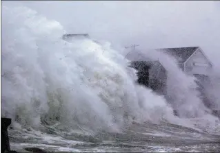  ?? SCOTT EISEN / GETTY IMAGES ?? MASSACHUSE­TTS: A wave crashes over homes Thursday in Scituate, Massachuse­tts. High tides coinciding with blasting winds pushed water ashore, causing coastal flooding in many parts of the Northeast. Areas of eastern Massachuse­tts and Rhode Island...