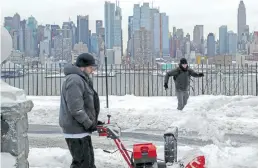  ??  ?? A resident clears the street of snow in Weehawken, New Jersey.