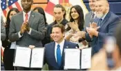  ?? RICH POPE/ORLANDO SENTINEL ?? Gov. Ron DeSantis holds up two house bills, HB 931 and HB 1317, after signing them on Thursday at Tohopekali­ga High School in Kissimmee.