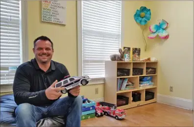  ??  ?? Joe Costolnick, Executive Director of Harbor House, sits in the toy room where children can play with various toys, read books and watch their favorite shows while they wait to be interviewe­d by a trained staff member. Many of the children who come to...