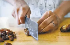  ??  ?? Top: Just Date Syrup creator Sylvie Charles mixes ingredient­s for tahini date chocolate chip cookies. Above: Charles chops fresh dates.