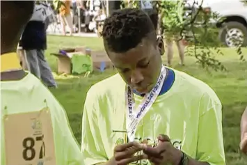  ?? KCTV ?? Ralph Yarl looks at a badge he received after walking at a brain injury awareness event last May. The family of Yarl, a Black teenager who was shot when he mistakenly went to the wrong home, filed a lawsuit Monday against the white 84-year-old homeowner, an attempt to put pressure on the criminal trial scheduled for later this year.