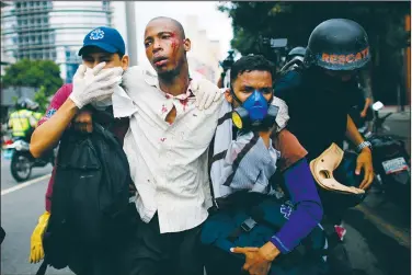  ?? AP/ARIANA CUBILLOS ?? Paramedics assist a man injured during clashes with security forces Thursday during protests asking for the resignatio­n of President Nicolas Maduro in Caracas, Venezuela.