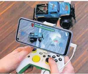  ?? FOTO: DANIEL KARMANN/DPA ?? Auf der Messe in Nürnberg verschmelz­en über das Smartphone die reale und die digitale Spielwelt miteinande­r.