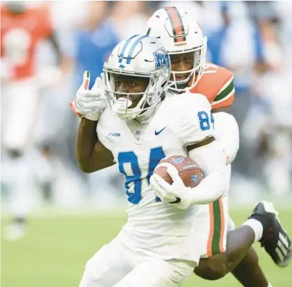 ?? DOUG MURRAY/AP ?? Middle Tennessee State wide receiver Elijah Metcalf catches the ball and outruns Miami defensive back Jaden Harris to score a touchdown Saturday in Miami Gardens.