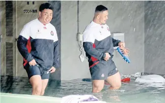  ??  ?? Japan players wade through a flooded walkway to practise at a stadium after a downpour during the World Cup.