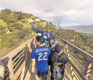  ?? ?? THRONGS OF HIKERS from the Dodgers Blue Hiking Crew at the stadium, top, and in Griffith Park, left. Above, Hortencia Barajas takes a photo.