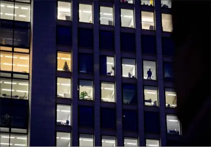  ?? MICHAEL PROBST — THE ASSOCIATED PRESS FILE ?? A man looks out of the window of an office building in Frankfurt, Germany, on Dec. 6, 2022. A new report says climate commitment­s by companies aren’t always as green as they seem. The report published Monday concludes that major brands are exaggerati­ng how ambitious their efforts to cut greenhouse gas emissions are, essentiall­y misleading consumers, investors and government­s.