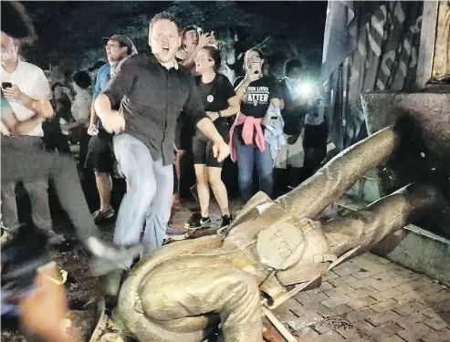  ?? JULIA WALL / THE NEWS & OBSERVER VIA THE ASSOCIATED PRESS ?? Protesters celebrate after the Confederat­e statue known as Silent Sam was toppled on the campus of the University of North Carolina in Chapel Hill in a demonstrat­ion on Monday night.