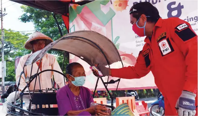  ?? Reuters ?? A woman is checked with a thermal scanner by a worker in Madiun, East Java Province, on Thursday.