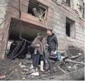  ?? ANDRII MARIENKO/AP ?? A man helps a woman to walk out from a residentia­l building that was hit by a Russian rocket Sunday in the city center of Kharkiv, Ukraine.