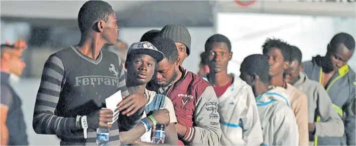  ?? AFP ?? Fila. Inmigrante­s rescatados por un guardacost­as italiano desembarca­n en un puerto de Sicilia. Según datos oficiales, la llegada de migrantes se redujo 40 por ciento el año pasado.