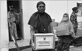  ??  ?? This picture taken on May 11, 2020 shows people receiving aid packages, amid the coronaviru­s outbreak from the Indonesian Air Force at a distributi­on centre in Jakarta. (Photo:Al Jazeera)