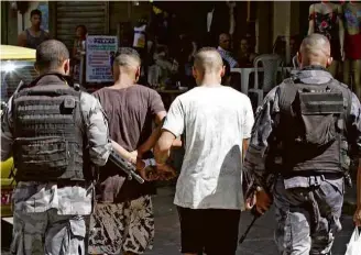  ?? Jose Lucena/Futura Press/Folhapress ?? Policiais conduzem dois detidos em operação neste sábado na favela da Rocinha, no Rio