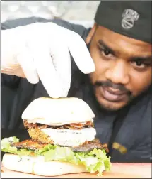  ??  ?? In this March 1, 2017 photo, chef Miguel Navarro inspects a Le Bleu hamburger, made with caramelize­d onions and blue cheese on top of portobello mushroom and lettuce, at the Atlas Meat-Free Delicatess­en in Miami. (AP)