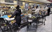  ?? NAM Y. HUH — THE ASSOCIATED PRESS ?? Customers wait for orders at a grocery store in Wheeling, Ill., Jan. 19. On Friday, the Commerce Department issued its report on consumer spending that showed that prices rose just 0.2% from November to December, a pace consistent with pre-pandemic levels and barely above the Fed’s 2% annual target.