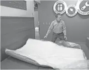  ?? MICHAEL SEARS / MILWAUKEE JOURNAL SENTINEL ?? Tom Metz, vice president of product developmen­t for Verlo Mattress, sets up a compressed mattress. The mattress is ready to sleep on right after unboxing but will come to full height in 24 hours.