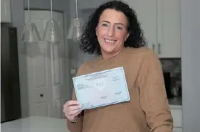  ?? John Colombo/For the Post-Gazette ?? Liz Mancing holds her nursing license at her home in Cranberry.