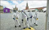  ?? AP ?? Volunteers in protective gear gather to clean an area of an outdoor n
book market set up at Red Square in Moscow on Saturday.