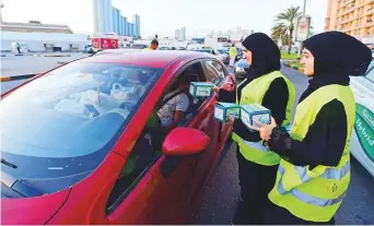  ??  ?? Ramadan volunteers give iftar parcels to motorists in Ajman.