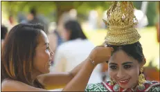  ?? (NWA Democrat-Gazette File Photo/J.T. Wampler) ?? Grets Molea (left) helps Pan Euper with her traditiona­l Thai garb during the fourth annual Internatio­nal Festival at the Botanical Garden of the Ozarks. Euper was preparing to perform a traditiona­l Thai dance. The 2019 event featured interactiv­e booths with displays and activities from different countries along with traditiona­l dance and musical performanc­es.