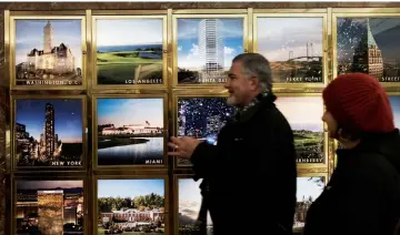  ??  ?? People walk by pictures of Trump properties in Trump Tower in midtown Manhattan in New York City. — AFP photo