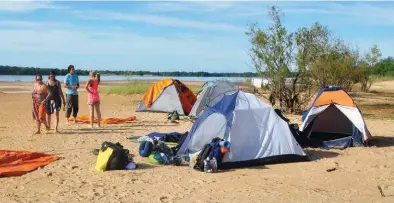  ??  ?? Arriba: a pleno sol en la segunda jornada en el campamento de la isla El Caygüé, antes de seguir la travesía. Abajo: parte del grupo encara el Alto Paraná hacia la isla Limosna, promediand­o el viaje a Itatí.