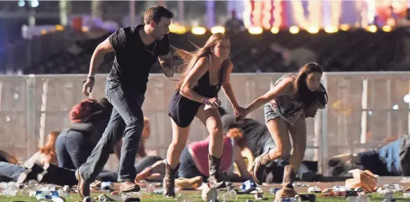  ?? DAVID BECKER/GETTY IMAGES ?? People run after a man in a nearby hotel opened fire on concertgoe­rs attending the Route 91 Harvest country music festival Sunday in Las Vegas.