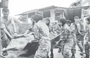 ?? — Gambar Bernama ?? GOTONG-ROYONG: Anggota Askar Wataniah membuang tikar surau yang musnah akibat banjir kelmarin di Taman Penang Free School semalam.