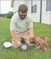  ?? [DAWES ARBORETUM] ?? Lowe demonstrat­es how to use a coffee filter to keep soil from washing out of the drainage hole of a container.