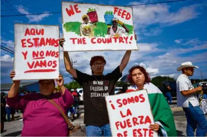  ?? REBECCA BLACKWELL/AP ?? Jonathan Martinez, 22, center, whose Mexican parents first worked on farms when they arrived in the US more than two decades ago, held a sign along with his sister Paola, right, a 19-year-old student, against Florida Senate bill 1718 on June 1 in Immokalee, Fla. Paola held a sign that read, in Spanish, “We are this country’s strength,” while another woman’s sign read, “We are here and we aren’t leaving.”