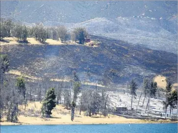  ?? Francine Orr Los Angeles Times ?? A FAST-MOVING brush fire near Castaic Lake grew to 800 acres and burned two outbuildin­gs Sunday. In the evening, firefighte­rs reported that the blaze was 20% contained. Crews battled four other fires that day.