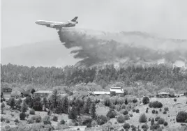  ?? EDDIE MOORE The Albuquerqu­e Journal ?? A slurry bomber dumps fire retardant between the Calf Canyon/Hermit Peak Fire and homes on the westside of Las Vegas, N.M., on Tuesday. Several types of aircraft joined the fight to keep the fire away from the northern New Mexico town.