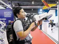  ?? Bloomberg News/SEONG JOON CHO ?? An attendee tries out a TRD Consultanc­y Ltd. Orion-7 MP (manpack) “drone slayer” at the Singapore Airshow.
